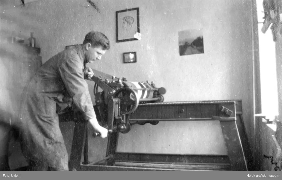 En ung mann arbeider med en maskin. Dette er en prøvetrykkpresse for firefargetrykkklisjeer.

Albumtekst: 
"La rullan gaa.
Utføres i arbeidstiden av operasanger G.W."
1919