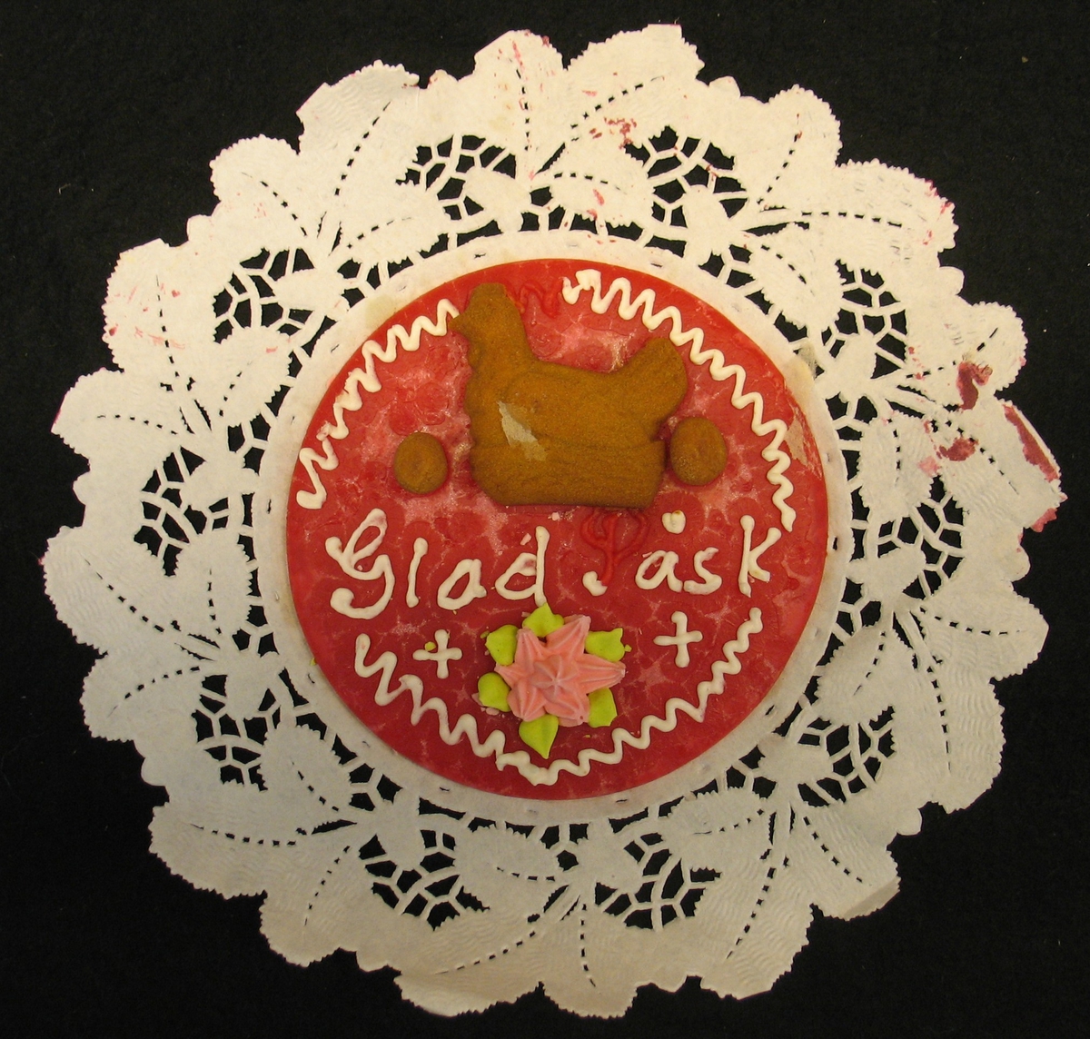 Påskkaka av kristyr. På en genombruten papperstablett. Som dekor finns tre bruna ägg, tre blommor och texten ''Glad Påsk''
 
Typisk kaka tillverkad av konditori i Åmål.
Bilaga finns.