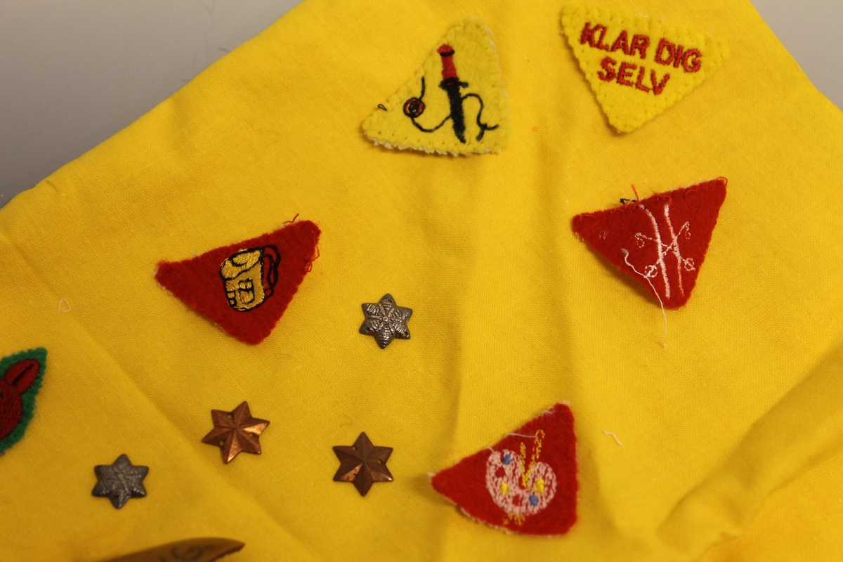 Skjerf med mange merker og stjerner som kunne syes på. Også speiderknute.