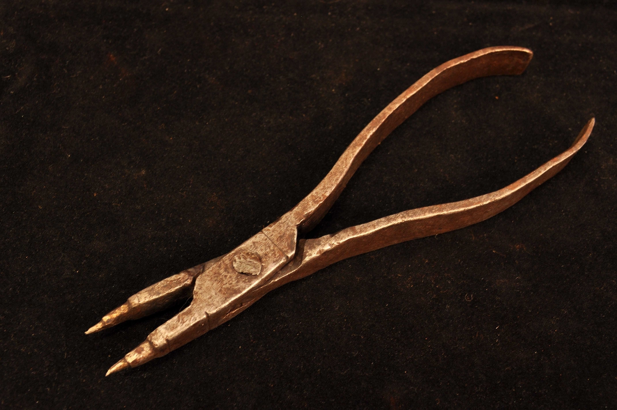 Fra protokollen: Tong, "skjentong", med flate handtak og trinnvis tilspissa nebb. L. = 19 cm.