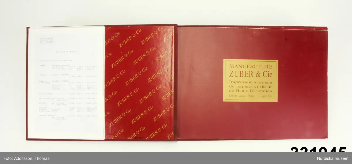 Tapetprovbok med vinröd pärm. På pärmens utsida, text i guld: "ZUBER PANORAMIQUES II". På försättsbladet: "ZUBER & CIE Impression à la main de papiers et tissus de Haute Décoration. Rixheim-Alsace- France. Depuis 1797".

Provboken innehåller prover på panoramatapeterna Pompei, Atrium, De 4 årstiderna, Golfo di Napoli, Les Antilles, La Grece, La Chasse och Terasses Romaines. Motiv ur tapeterna presenteras i sin helhet genom fotografier där vådernas mått och motivets hela mått redovisas. Ett par prov av produkten, två färgalternativ av ett stycke tapet som föreställer ett fartyg, på tapeten Les Antilles.

Panoramatapeterna består av motiv i 2-7 våder i bredderna 140-490 cm. Totalhöjd 290 cm. Priset på tapeterna var 1988 4787-17190 kr/ motiv.

På insidan av pärmen en prislista.
/Maria Maxén 2013-10-08