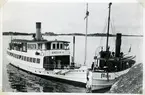 Båda fartygen förhyrda av Kungliga Svenska Segelsällskapet (KSSS)  under en Sandhamnsregatta ca 1910-1915. RN 4438.
Till höger bogserbåten Frigga ex Hero tillhörig Stockholms Transport & Bogserings AB.
Gastholmsgrundet i södra Kanholmsfjärden