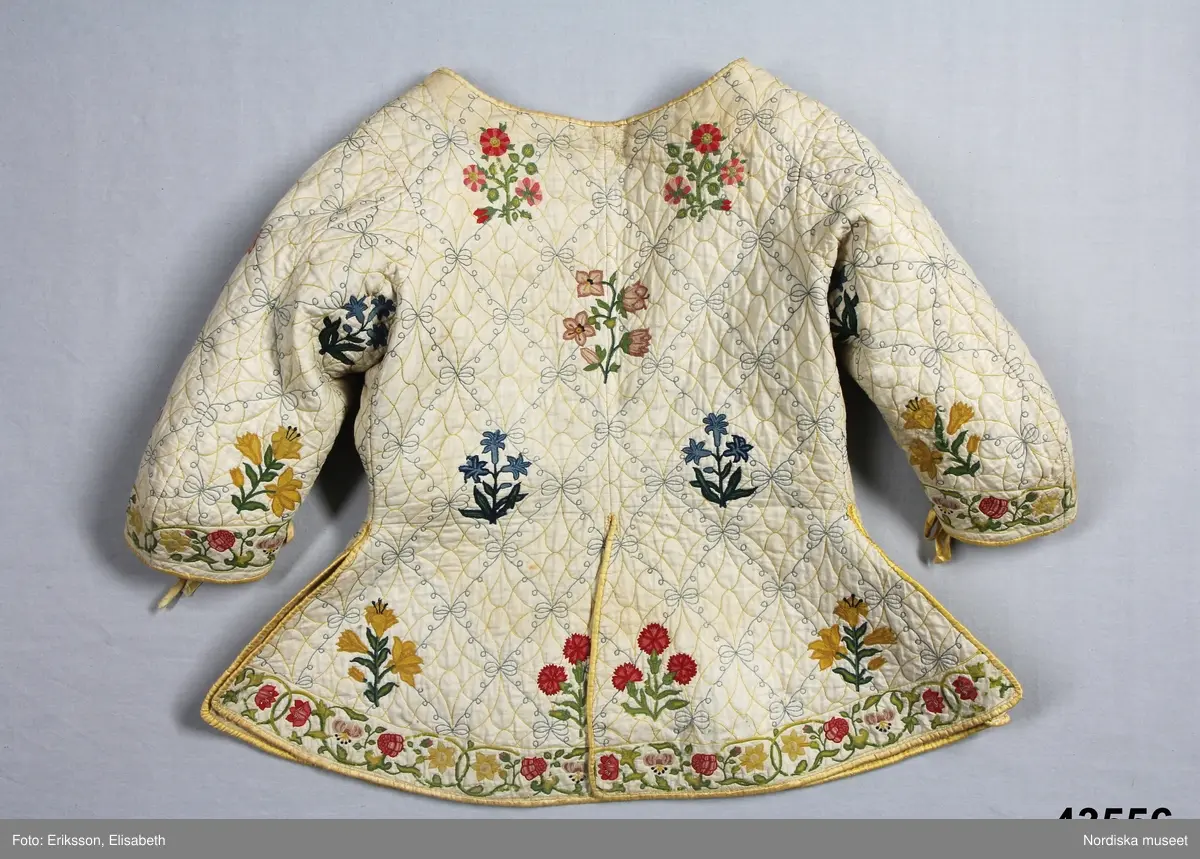 Katalogkort IV:
"Tröja / kofta, för dam, 1600-talets slut.
Längd 54 cm
Av linnelärt med foder av glest tuskaftat ylletyg. Försedd med stickningar i gult och blått samt broderier i kedje-söm med yllegarn. 2 ryggstycken, 2 framstycken. Halvlånga ärmar med 2 sömmar, varav den ena öppen och kantad med gult siden samt försedd med gult silke tränsade snörhål, med band av dubbelvikt sammansytt band. Sömarna uppslitsade nedifrån upptill midjan och kantade med gult siden."