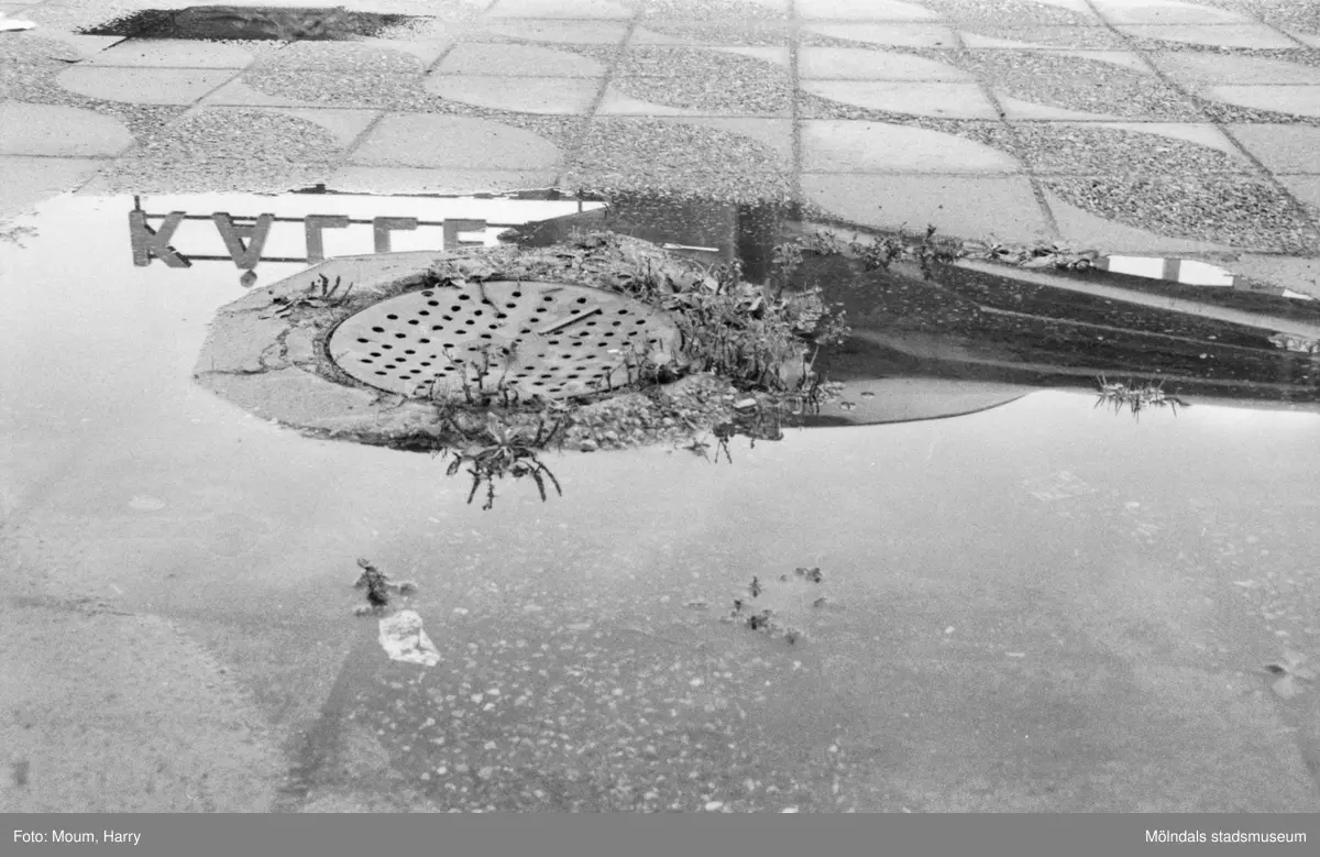 Dåligt underhållen vägbana i Kållereds centrum, år 1984. "Trappan är sönder och brunnarna fungerar ej. Slarv i Kållered centrum!"

För mer information om bilden se under tilläggsinformation.