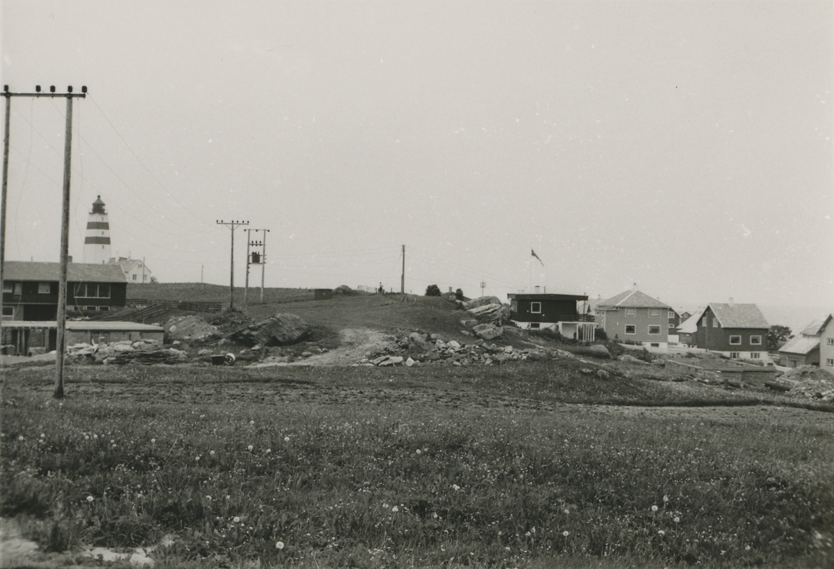 Parti ved Alnes fyr på Godøy. Flere hus og en strømlinje i forgrunnen.