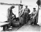 'Naturhistoriska muséets Skagerackexpedition med båten Skandia sommaren 1934: ::  :: 4 män på Skandias däck, 1 man tömmer stor håv i trätunna. Leonard Axel Jägerskiöld sittande till höger. ::  :: Ingår i serie med fotonr. 3309-3317.'