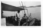 'Naturhistoriska muséets Skagerackexpedition med båten Skandia sommaren 1934: ::  :: 3 män på båtdäckt, en av dem läser i en tidning. ::  :: Ingår i serie med fotonr. 3309-3317.'