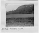 'Vy med åkerfält i förgrunden och gård nedanför delvis skogsklätt berg. :: Enligt bildtext: Bild 3: Pilgrimsfalk, boplats i Halleberg. ::  :: Ingår i serie med fotonr. 3730-3732.'