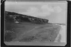 Vy med öppna gräsmarker, grusväg. Vy med landborg av kalksten. Sedimentära lager.