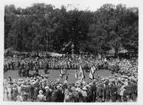 Folksamling på gräsmattan, sommar. Hattklädda. Ev scouter se fotonr. 5021. Samlade på öppen gräsyta.