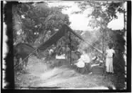 'Diverse fotografier från bl.a. dåvarande Nordrhodesia, nu Zambia, tagna av Konsul Magnus Leijer. ::  :: Tre personer vid ett tält. 1 st man ståendes utanför, 1 st kvinna och 1 st man sittandes framför. Kvinnan med bebis i famnen, sittande mannen matar en häst.'