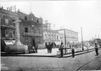 'Diverse fotografier från bl.a. dåvarande Nordrhodesia, nu Zambia, tagna av Konsul Magnus Leijer. ::  :: Ett torg i en stad, Byggnader i bakgrunden. På torget står en kors-staty samt parkbänkar. Människor kring statyn samt på torget och gatan.'