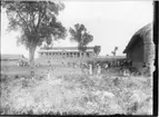 'Diverse fotografier från bl.a. dåvarande Nordrhodesia, nu Zambia, tagna av Konsul Magnus Leijer. ::  :: Ett större antal människor utanför en tegelmur omgärdande en tegelbyggnad, vid muren ytterligare 2 byggnader av olika storlekar.'