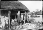 'Diverse fotografier från bl.a. dåvarande Nordrhodesia, nu Zambia, tagna av Konsul Magnus Leijer. ::  :: 1 st man murar en cirkulär byggnad, bredvid honom står 3 st män. I bakgrunden sitter en grupp människor framför en annan byggnad.'