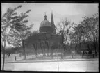 'Vy med stor byggnad, katedral, med park, torg där människor promenerar. Planterade träd. ::  :: Ingår i serie med fotonr. 5278:1-21. Se även fotonr. 5269-5292 med bilder från Stuxbergs resa till Kaukasien.'