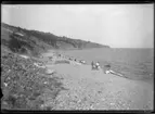 'Vy över strand och hav, människor på stranden. Berg omkring. ::  :: Ingår i serie med fotonr. 5280:1-17. Se även fotonr. 5269-5292 med bilder från Stuxbergs resa till Kaukasien.'