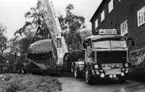 'Göteborgs Naturhistoriska museum november 1978: :: Maskinell lastning med lyftkran? av 30 ton tunga blocket av vindslipad ögongnejs, skänkt 1963. Transport med Gamlestadens lastbilar från södra gaveln till östra ytterväggen utanför nuvarande huvudentré. ::  :: Ingår i serie med fotonr. 5527:69-216.'