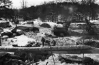 'Tillbyggnaden av Göteborgs Naturhistoriska Museum februari 1979. Vy över byggarbetsplatsen och ut mot Slottsskogen. Grävmaskin, snö och byggarbetare. ::  :: Ingår i serie med fotonr. 5527:69-216.'