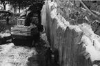 'Tillbyggnaden av Göteborgs Naturhistoriska Museum februari 1979. Bergväggen efter sprängningen av berget. Tre personer, snö och en grävmaskin, Lennart Lundquist i Kungälv., Byggnader, Geologi ::  :: Ingår i serie med fotonr. 5527:69-216.'