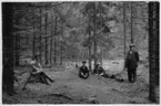 '4 män, sittande, liggande och stående i liten glänta i granskog. ::  :: Fotonr. 7046:234-275 indelade som ''Naturskogsbestånd i Göteborgs län och Bohus län''. Ingår i serie med fotonr. 7046:1-383, 7047:1-33 och 7048:1-67 med bilder från  Länsjägmästare John Lindners bildarkiv.'