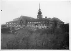 'Naturhistoriska museet i Slottsskogen, sett från Linnéplatsen, med byggnadsställningar vid burspråket i biblioteket och runt tornet. ::  :: Samma motiv i artikel ''Slottsskogsmuseet låter ridån fall'' i Göteborgs Posten 1918-11-22. Dossier s.70.'