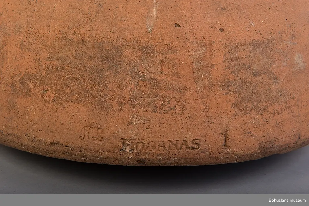 Form av rödbränt gods. Vertikal spricka i nerkanten, 15 cm lång.
Ur handskrivna katalogen 1957-1958:
Tre gjutformar f. toppsocker
c) H. 54; största D. 24 cm; lik föreg. saknar spån. Hel.