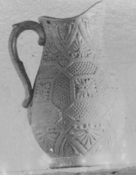 Vit tillbringare av fajans. Pip defekt. Stiliserad bladdekor i relief.