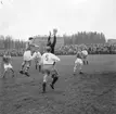 En målvakt hoppar upp för att fånga bollen i en fotbollsmatch.