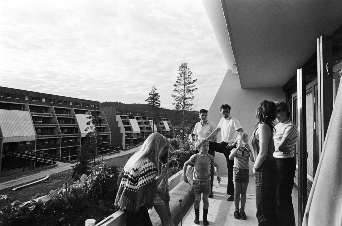 En gruppe mennesker står på en terrasse i en terrasseblokk på Vestli.