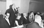 FRÅN POSTVERKETS MEKANISKA VERKSTADS 50-ÅRSJUBILEUM, 1964. Supé på Hotell Malmen, Stockholm, den 2 mars 1964. Vid mikrofonen står nuvarande verkstadschefen Börje Ragnerstam