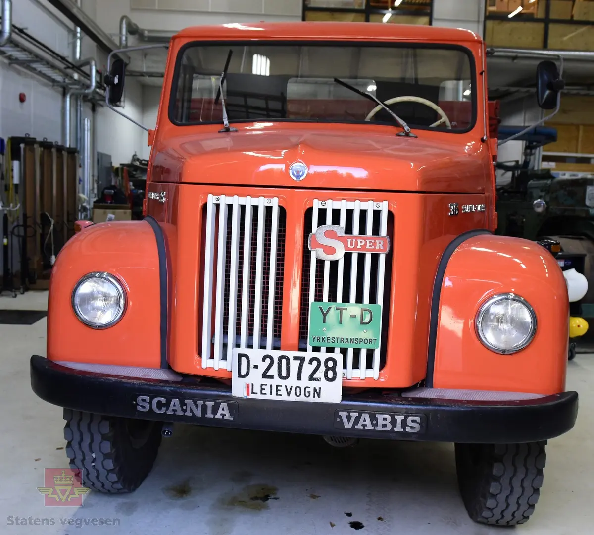 Lastebil på 6 hjul, (to akslet) med bakhjuls drift. Akselavstand 4,2 meter.  I hovedsak oransje. Motoren er en turbomatet 4-sylindret dieselmotor av typen Scania-Vabis DS5, den yter 120 hestekrefter og har et sylindervolum på 5193 kubikkcentimeter. Girkassen er en manuell 5-trinns synkronisert utgave, høy- og lavgir i bakakslingen (two-speed) gir tilsammen 10 gir pluss revers. Bremsene er drevet av trykkluft. Bilen har lasteplan med karmer og et ekstra sett karmer på toppen. Bilen har 3-veis hydraulisk tipp fra Thanstrøm i Halden. Svart interiør, lakkert grå innvendig. Egenvekten er ca. 5,1 tonn, lasteevne ca. 5,825 tonn. Totalvekt 11 tonn.
Farge: paprika rød.