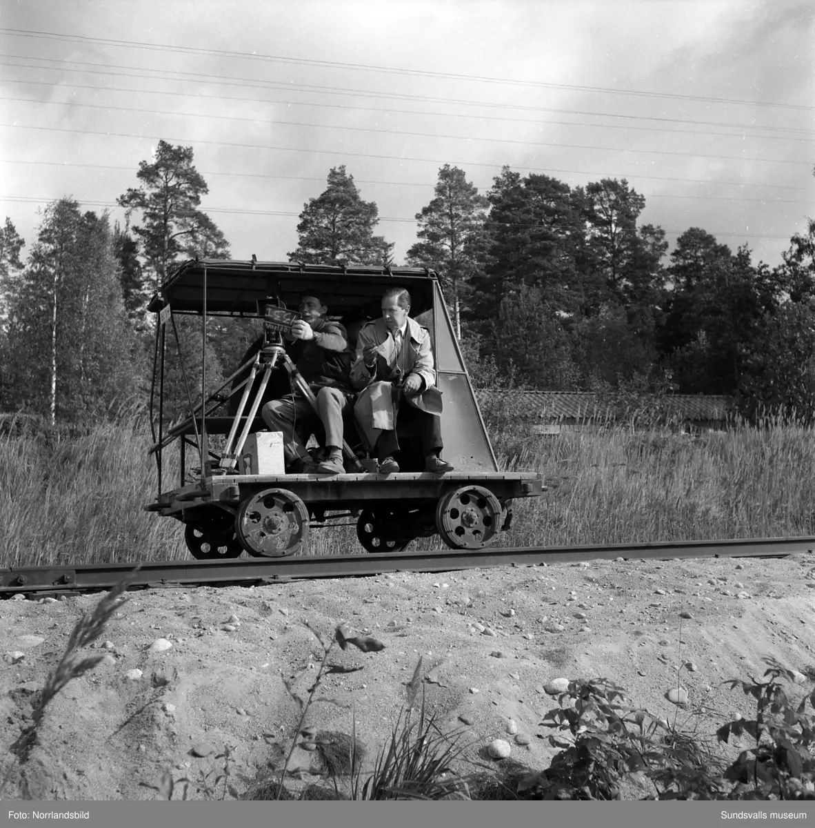 Filminspelning av Nordisk Tonefilm för Transportarbetareförbundet. I bakgrunden syns Östrandsfabriken med de numera rivna tjänstemannabostäderna på Näsberget. På en av bilderna filmar man vid Shellmacken mitt emot kyrkan invid riksvägen ( i Timrådalen. Byggnaden finns fortfarande (2015) kvar liksom det stora huset bakom bensinstationen (Drevvägen 5).