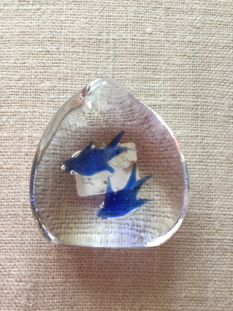 Liten glasprydnad i genomskinligt glas med två blå fåglar ingjutna i glasmassan.