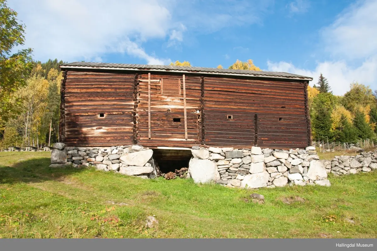 Dette er en stall med trev.  Den er sammensatt av flere tømmerhus som trolig er bygd en gang mellom 1825 og 1850 her på Skaga.  Annen etasje er utkraget og den har bordtak.
