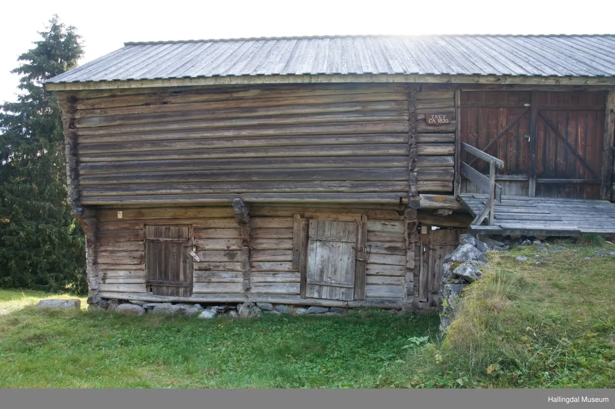 Dette er en stall med trev.  Den er sammensatt av flere tømmerhus som trolig er bygd en gang mellom 1825 og 1850 her på Skaga.  Annen etasje er utkraget og den har bordtak.
