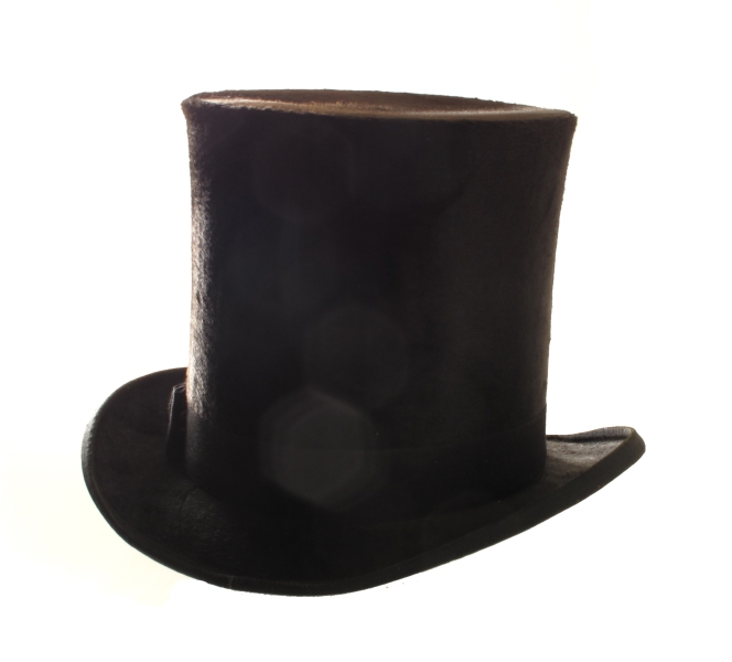 Flosshatt i hatteeske, merket hattemaker P. A. Paulsen, Arendal. a) Flosshatt. Sort floss, purpurfiolett og vinrødt for, trykt med gull midt i bunnen: P. A. Paulsen, Arendal. Svettebrem av konjakkfarget lær. Sort ripsbånd m. sløyfe.   
b) Hatteeske. Brunt lær, lærhank med messingbeslag, hvorpå innripet: T. Tellefsen. Foret med gammelrosa fløyel, innv. i bremmen gammelrosa tynt stoff.