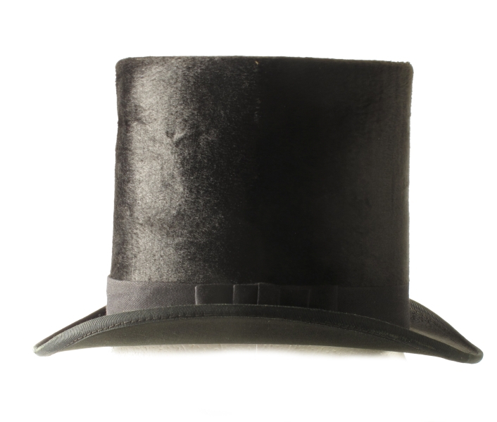 Flosshatt i hatteeske, merket hattemaker P. A. Paulsen, Arendal. a) Flosshatt. Sort floss, purpurfiolett og vinrødt for, trykt med gull midt i bunnen: P. A. Paulsen, Arendal. Svettebrem av konjakkfarget lær. Sort ripsbånd m. sløyfe.   
b) Hatteeske. Brunt lær, lærhank med messingbeslag, hvorpå innripet: T. Tellefsen. Foret med gammelrosa fløyel, innv. i bremmen gammelrosa tynt stoff.