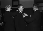 Man får medalj av landshövding Hilding Kjellman, med assistans av kvinna. Uppsala i april 1945