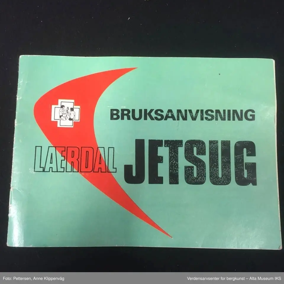 A. Sylinderformet plastapparat med tilfestet gummislange og gjennomsiktig plasttut.  Inneholder en driftspatron fylt med ufarlig gass.
B Rektangulært hefte, bruksanvisning.