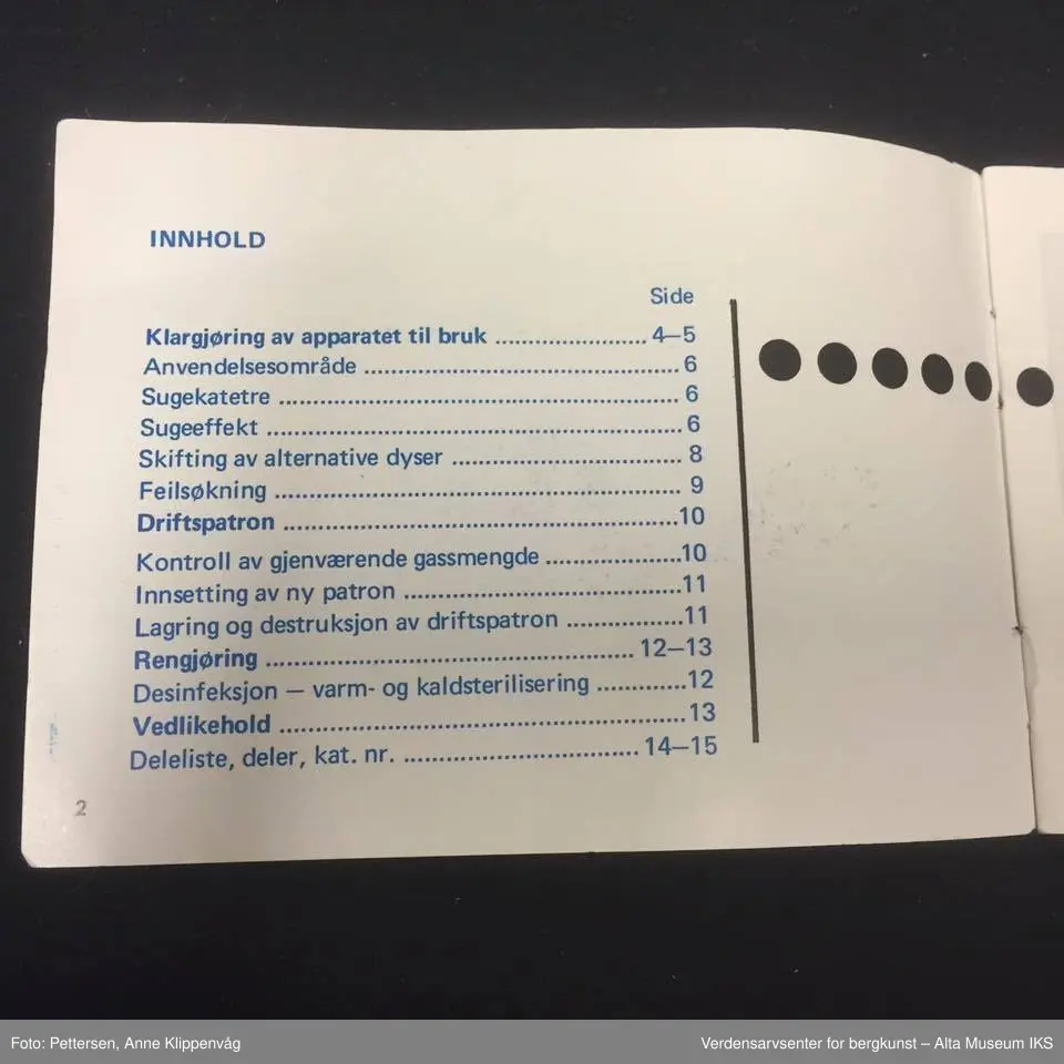 A. Sylinderformet plastapparat med tilfestet gummislange og gjennomsiktig plasttut.  Inneholder en driftspatron fylt med ufarlig gass.
B Rektangulært hefte, bruksanvisning.
