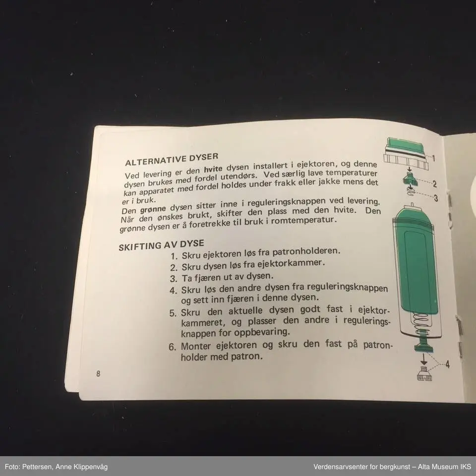 A. Sylinderformet plastapparat med tilfestet gummislange og gjennomsiktig plasttut.  Inneholder en driftspatron fylt med ufarlig gass.
B Rektangulært hefte, bruksanvisning.