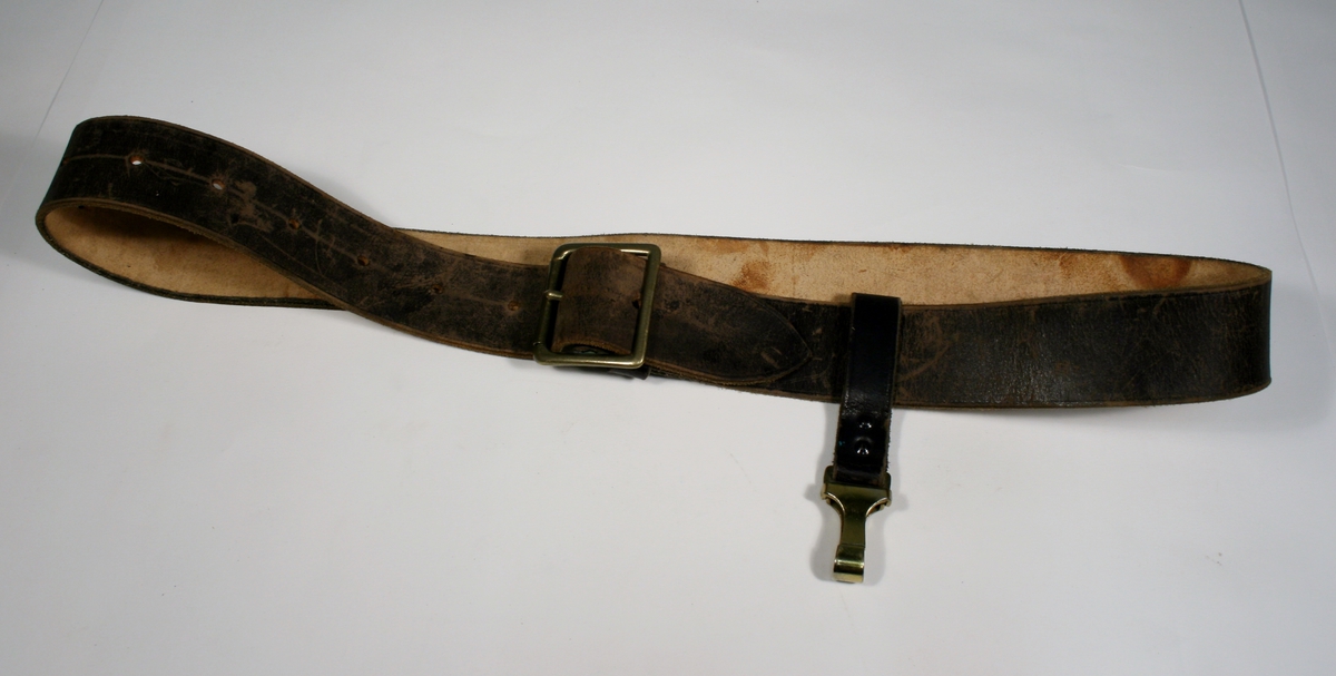 Bandolær i brunt skinn med spenner i messingfarget metall.