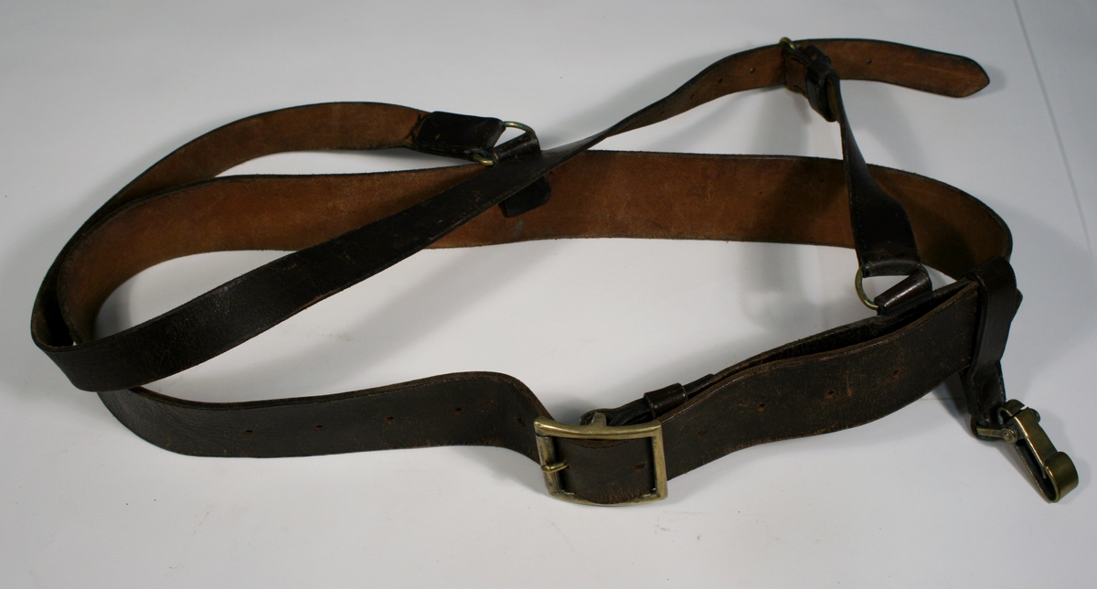 Bandolær i brunt skinn med spenner i messingfarget metall.