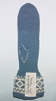 Damkragvante i dubbelt 3-trådigt lj blått ullgarn. 
1cm resår,slätstickad,naturvit och ljusblå blomsterbård,6cm resår ,
handen moss-stickad,tummen och avmaskning,slätstickad