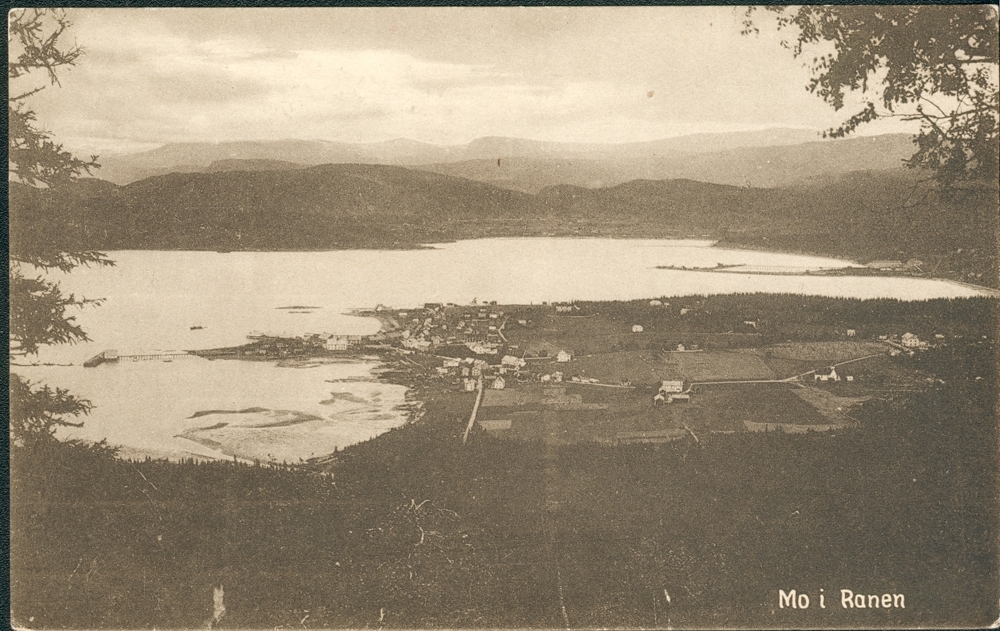 Prospektkort. Mo. Oversiktsbilde tatt fra Mofjellet. Moholmen t.v. Mo Prestegård midt i det. På bildet sees i bakgrunnen fra venstre, Båsmo, Ytteren og Guldsmedvik