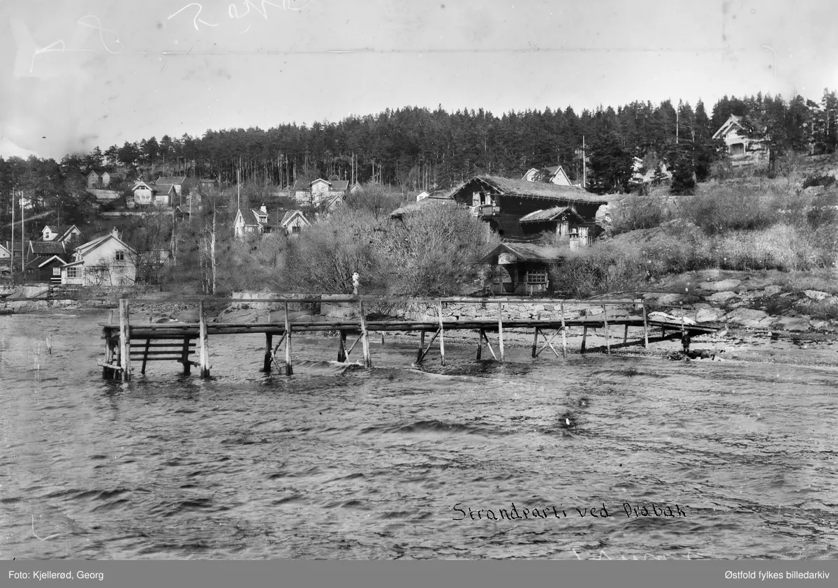 Brygge i Drøbak.
Eiendommen til kunstneren Ludvig Skramstad, ligger like syd for gamle Drøbaks grenser. Ligger helt syd i Johanne Dybwads vei. Han kom til Drøbak i 1902 og bygde sitt nye hus i laftet tømmer og dragestil. trebryggene i bildet hadde kort levetid pga. isgang vinterstid. Reparasjon av brygger var en fast vårlig fornøyelse!