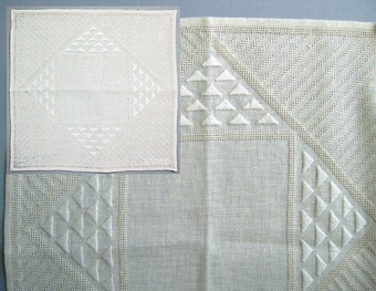 En broderad duk och ett broderiprov i linne. Broderi i rätlinjig plattsöm och myrgång i blekt lingarn på blekt linneväv. Geometriskt mönster; trianglar och diagonala linjer.
WLHF-0466:1 Broderiprov. Mått 140 x 180 mm. Tunnare kvalité.WLHF-0466:2 Färdig duk. Mått 320 x 310 mm. Märkt med en lapp med texten: "Isblomma modell 144:- material 25.50". Grövre kvalité. På bild, bilden är ett montage med den färdiga duken samt detalj. Inte så vit i verkligheten.
WLHF-0466:3 Färdig duk. Mått 330x320 mm. Något ljusare och lite större än :2. Märkt tygetikett  "Hemslöjd-Föreningen Leksand" och etikett "Leksands Hemslöjds-vänner" samt pappetikett "Leksands Hemslöjdsförening  "Isblomma Skollinne II Pris: Matr 146:-"Mönsterskiss på rutpapper finns tillsammans med broderiprovet.Scannad till datamapp: "Tillbehör".