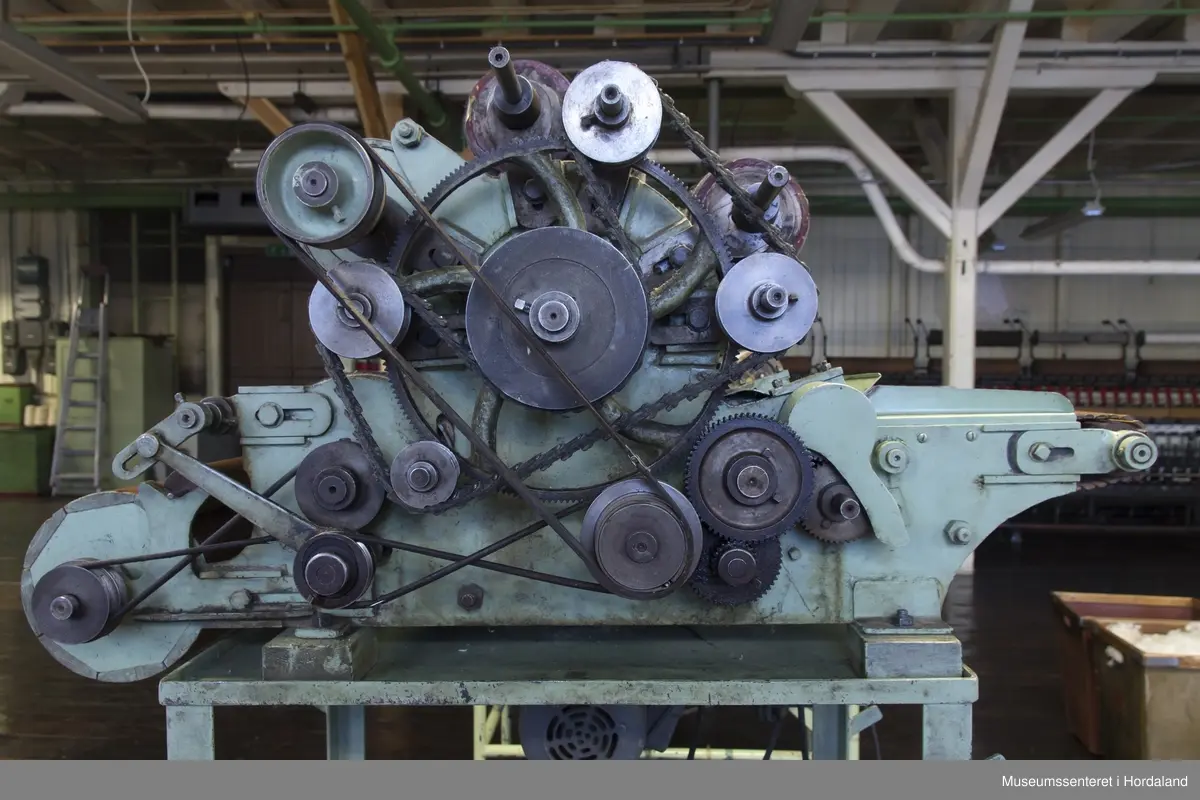 Mintgrøn prøvekardemaskin med tredetaljar, montert på stativ. Ukjend fabrikat.