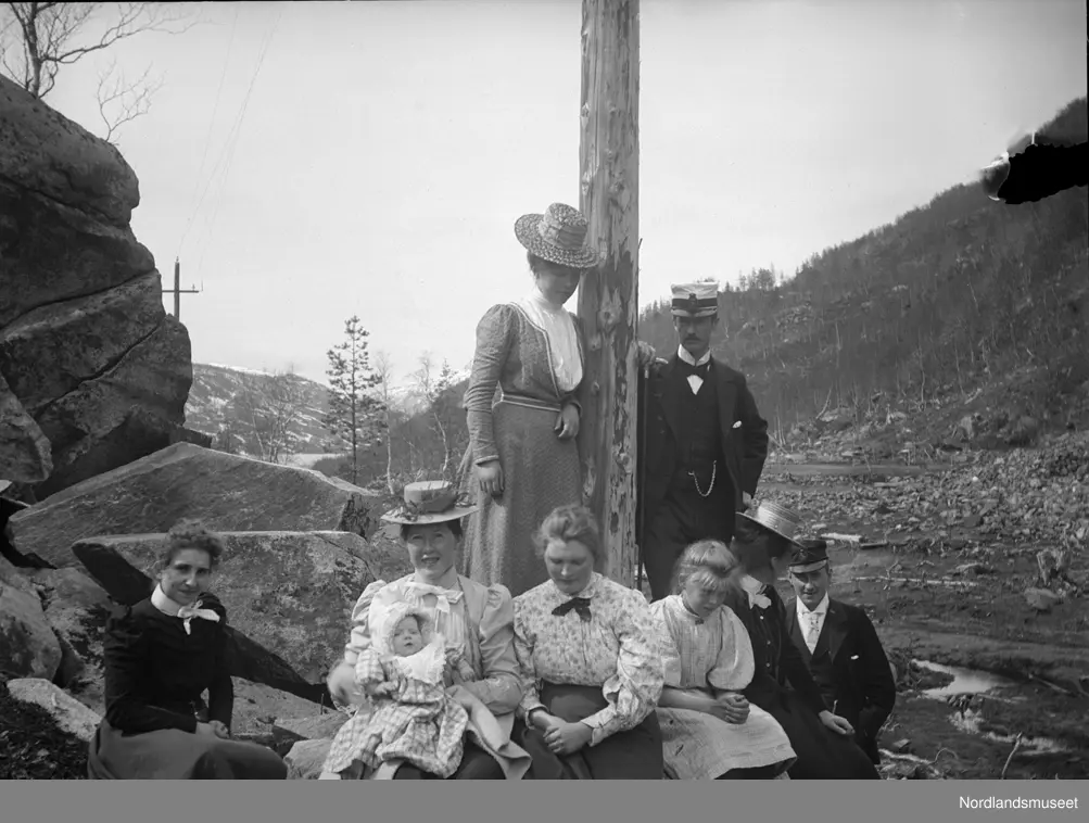 6 kvinner, to menn og et barn fotografert ute ved en telefonstolpe.