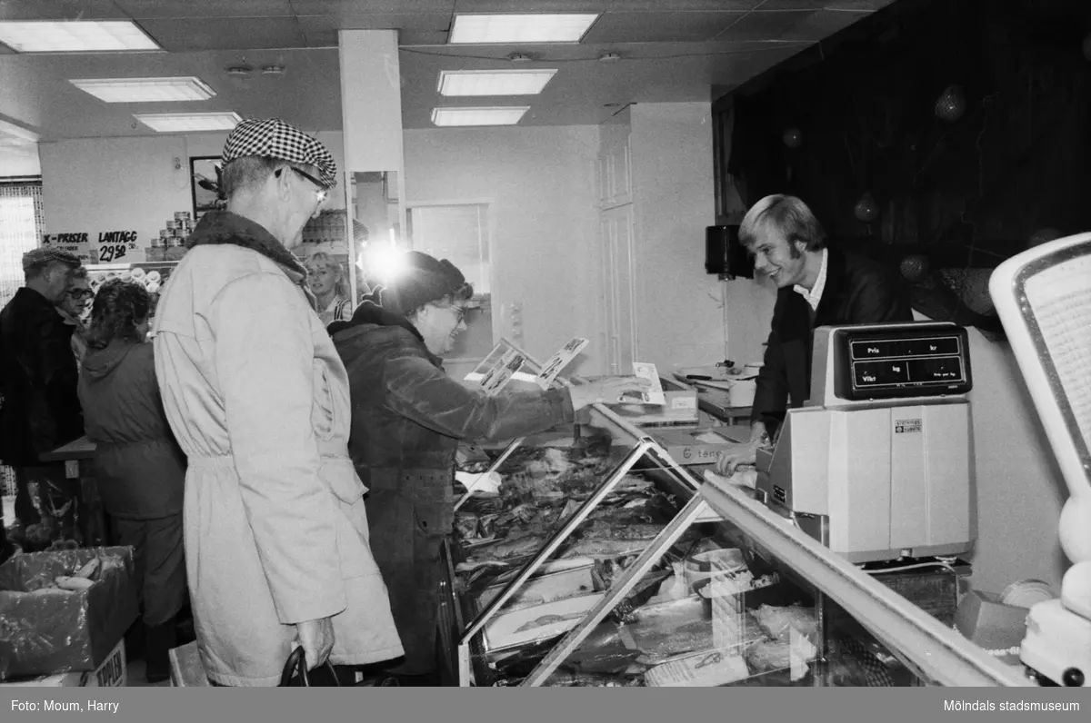 Ny fiskaffär, Fiskhörnan, på Hagabäcksleden i Kållereds centrum, år 1983. "Christer Augustsson betjänar kunder i sin nyöppnade affär."

För mer information om bilden se under tilläggsinformation.